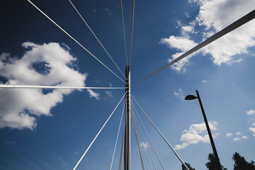 Upwards perspective of a suspension bridge over blue sky and a street light