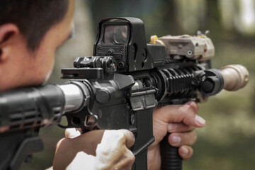 Military shooter with his precising assault rifle aiming and shooting target in the range