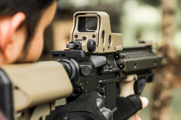 Military shooter with his precising assault rifle aiming and shooting target in the range