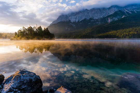 Beautiful and foggy Summer sunrise on the Eibsee lake in German Alps, southwest of Garmisch-Partenkirchen below the Zugspitze in the Wetterstein Mountains in Bavaria