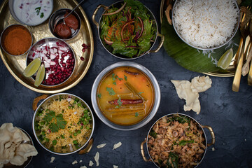 South Indian vegetarian food served on traditional platters  and trays, black background