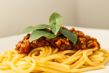 Macarrão vegano com molho de tomate e proteína de soja e folhas de manjericão.