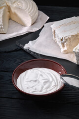 Yogurt or sour cream in rustic bowl on wooden background, top view