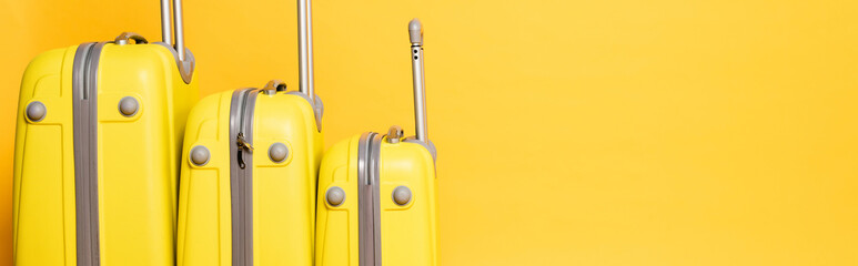 stack of travel bags isolated on yellow background, panoramic shot