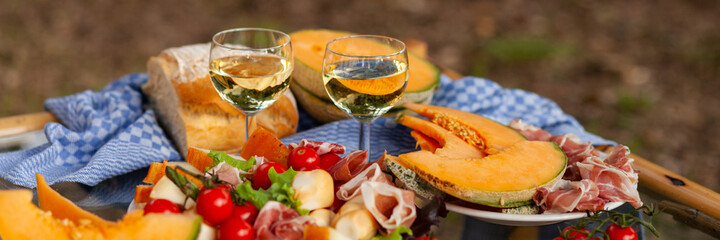 Delicious snacks for romantic dinner for a couple. Wine, fresh juicy seasonal fruits and vegetables, light food. Beautiful table decor, bright colors. Italy, Tiscany. Banner