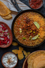 Vegan lentil stew in cast iron pan along with corn tortillas and side dishes