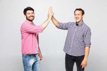 Portrait of two happy young men giving high five isolated over white background