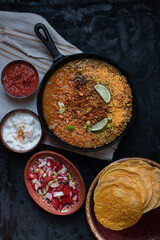 Vegan lentil stew in cast iron pan along with corn tortillas and side dishes, copy space