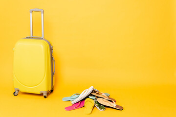 travel bag with colorful flip flops on yellow background