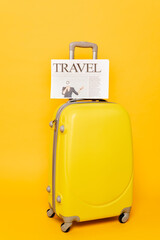 travel newspaper on colorful suitcase on yellow background