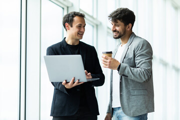 Business two men at informal meeting looking at laptop in the office building