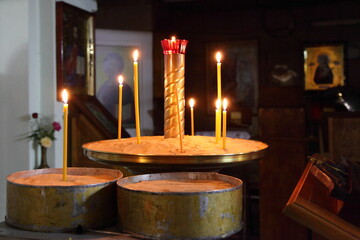 Church wax candles in sand candlesticks in interior on Icons background, religious ceremony of Christianity