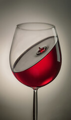 a glass of red wine with a drop on the surface inside