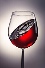 a glass of red wine with a drop on the surface inside
