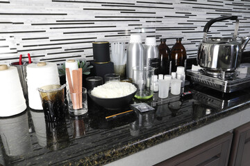 The material soy wax, fragrance and essential oil , wick and container tools for making candle are put on the marble table near the gas stove in the kitchen home