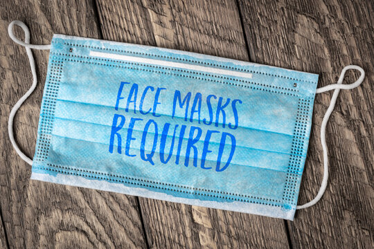 face masks required - text on a disposable mask, business sign during the coronavirus covid-19 pandemic and social distancing