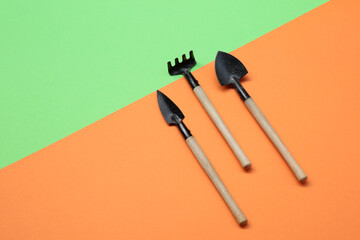 Small gardening supplies on orange and green backdrop.