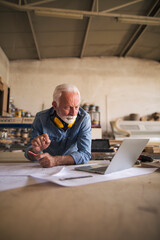 Engineer using laptop in a woodwork workshop