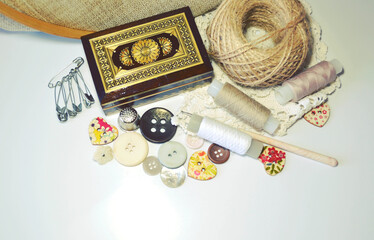 Sewing accessories in beige and ecru colours including vintage wooden box, sewing spools, buttons, jute cord. Scrapbooking and DIY. Hobby and needle work background. Retro style. 