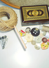Sewing accessories in beige and ecru colours including vintage wooden box, sewing spools, buttons, jute cord. Scrapbooking and DIY. Hobby and needle work background. Retro style. 