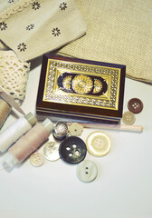 Sewing accessories in beige and ecru colours including vintage wooden box, sewing spools, buttons, scissors,  cotton lace, crotchet. Scrapbooking and DIY. Hobby and needle work. Retro style.  Closeup 