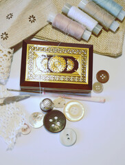 Sewing accessories in beige and ecru colours including vintage wooden box, sewing spools, buttons, scissors,  cotton lace, crotchet. Scrapbooking and DIY. Hobby and needle work. Retro style.  Closeup 