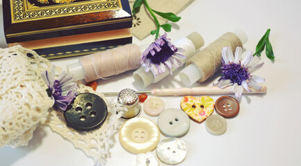 Sewing accessories in beige and ecru colours including vintage wooden box, cotton lace, sewing spools, buttons and flowers. Scrapbooking and DIY. Hobby and needle work background. Retro style 