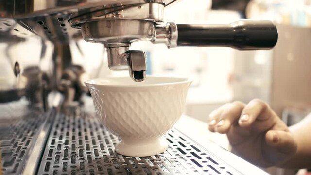 Hot coffee stream from coffee maker machine through fillter in white cup Flowing fresh ground coffee