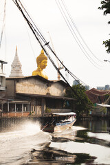 Big Buddha statue located by the river. And a boat was passing by : Pak Nam Phasi Charoen Temple, Bangkok, Thailand