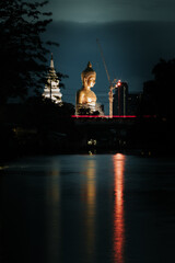Big Buddha statue located by the river. And a boat was passing by : Pak Nam Phasi Charoen Temple, Bangkok, Thailand