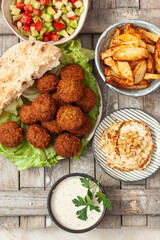 Traditional homemade chickpea Falafel balls  with vegetables salad , hummus, tahini sauce,chips and pita bread. Vegetarian food concept. 