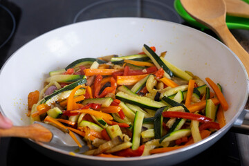 Colored mix of filleted fresh vegetables, courgettes, carrots, peppers and eggplants sautéed in a pan to be used for rolls