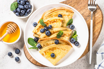 Crepes with blueberries at white table.