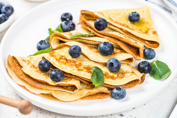 Crepes with blueberries at white table.