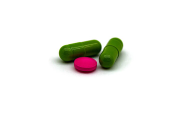Two medicinal capsules of green color and one tablet of pink color