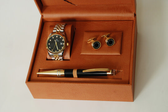 male formal clothing accessories gift box,wrist watch,pen and pair of cuff links set in brown leather box.soft focusing 