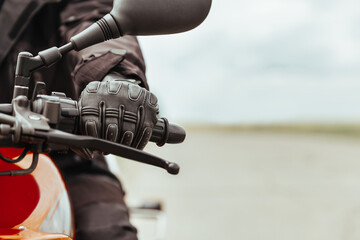 Man's hand in motorcycle protective gloves holds a motorcycle, close-up