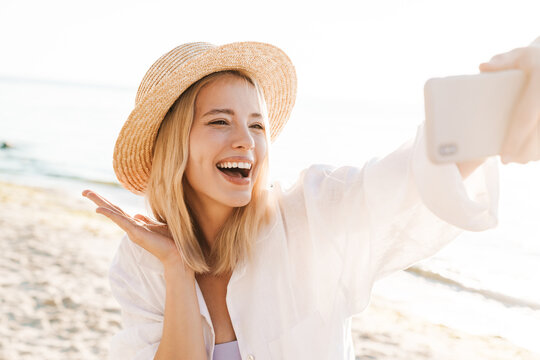 Image of woman blowing air kiss and taking selfie photo on cellphone