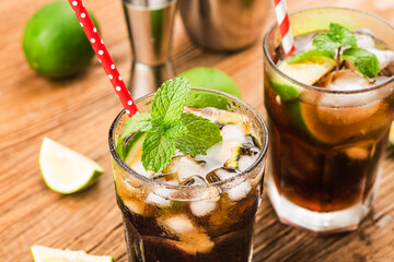 Fresh made Cuba Libre with brown rum, cola, mint and lemon on wooden background