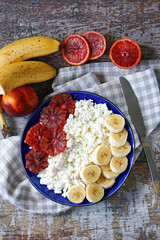 Selective focus. A healthy dessert or snack with cottage cheese and fruits. Cottage cheese with banana and orange on a plate. The keto diet.