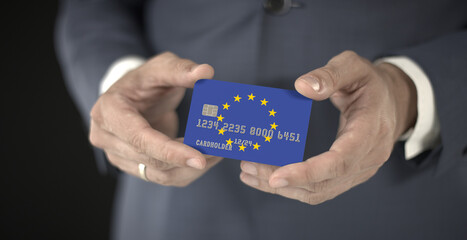 Businessman takes plastic bank card with printed flag of the European Union in his hands, fictional numbers