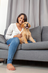 Woman sitting with her dog on sofa at home