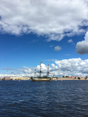 The water area of ​​the Neva with the sailing ship "Poltava", which arrived to take part in the naval parade in St. Petersburg against the background of a blue sky with clouds.