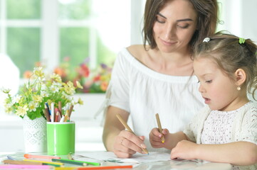 Fototapeta premium Cute girl with mother drawing at the table