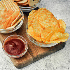 Chips, snacks and crackers on a wooden board. Fast food.