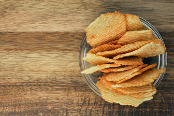 Corrugated potato chips on a wooden board. Snack, junk food. Close up.