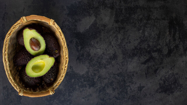Top view of hass avocado in a wicker basket. Cuted avocado in a basket witn copyspace