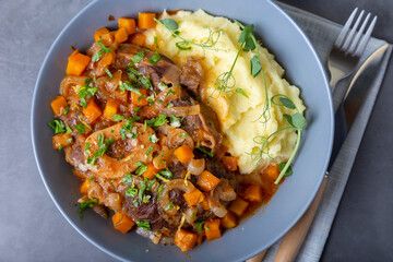 Ossobuco. Veal (beef) shanks with mashed potatoes, gremolata and sauce. Traditional Italian dish. Close-up.