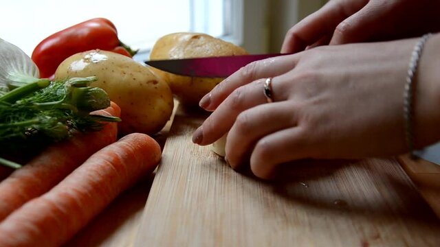 Girl chopping a onion with a knife on the cutting board. preparing to cook chicken soup or vegetable stew or salad