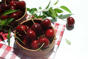 cherries in a wooden bowl close up and a checkered napkin top view. copy space